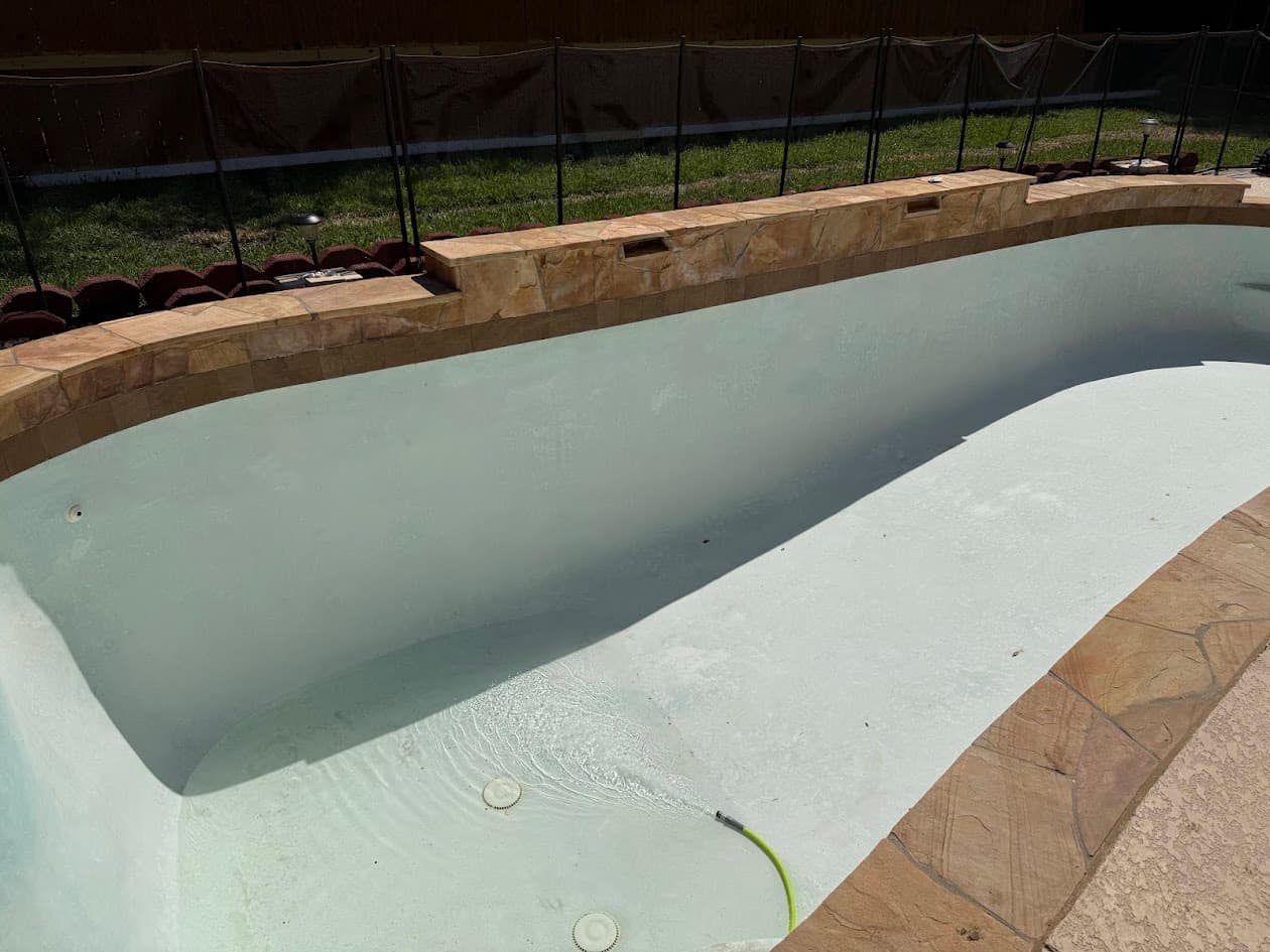 Same pool after sandblasting, drained and restored to a clean white plaster finish