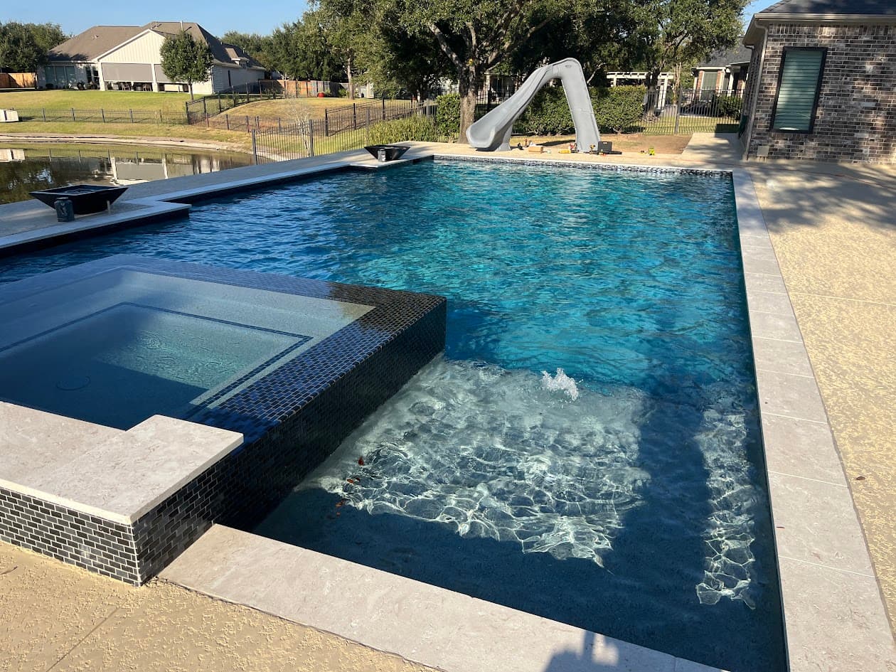 Luxury custom gunite pool with spa and slide built by CHR Builder in Katy TX